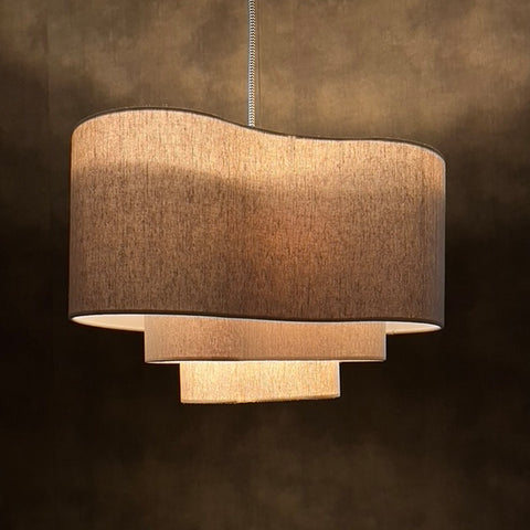 a beige lit 3 tiered lampshade in an unusual kidney shape