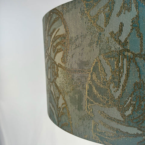 A luxurious peacock blue lampshade in rich jacquard fabric, with a gold tread pattern in the weave, designed to bring warmth and sophistication to your space