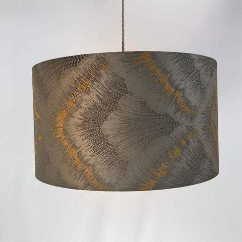 A luxurious silver drum lampshade crafted from premium jacquard fabric, featuring a refined god and silver design. The frosted clear inner lining and beach gold frame add a sophisticated touch to any space.