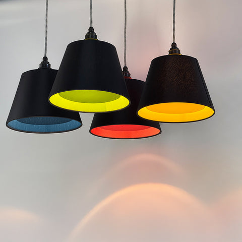 A group of primary and secondary coloured diffuser lampshades in black with matching inside colours in blue, gree, red and yellow