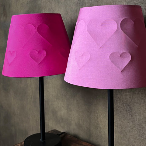 two different coloured pink empire lamp shades with embossed hearts against a brown textured background