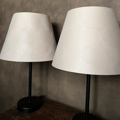 two embossed empire shades in light silk against a brown wall