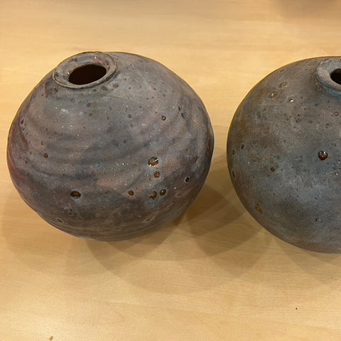 Two gray ceramic pots on a light wooden surface.