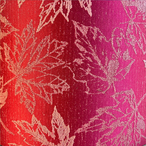A close-up of a luxurious fuchsia red jacquard fabric with a delicate embroidered maple leaf pattern.