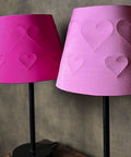 two different coloured pink empire lamp shades with embossed hearts against a brown textured background
