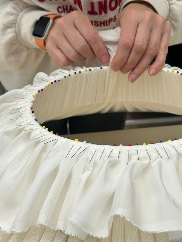 Close-up of a person adjusting pleated fabric on a lampshade.